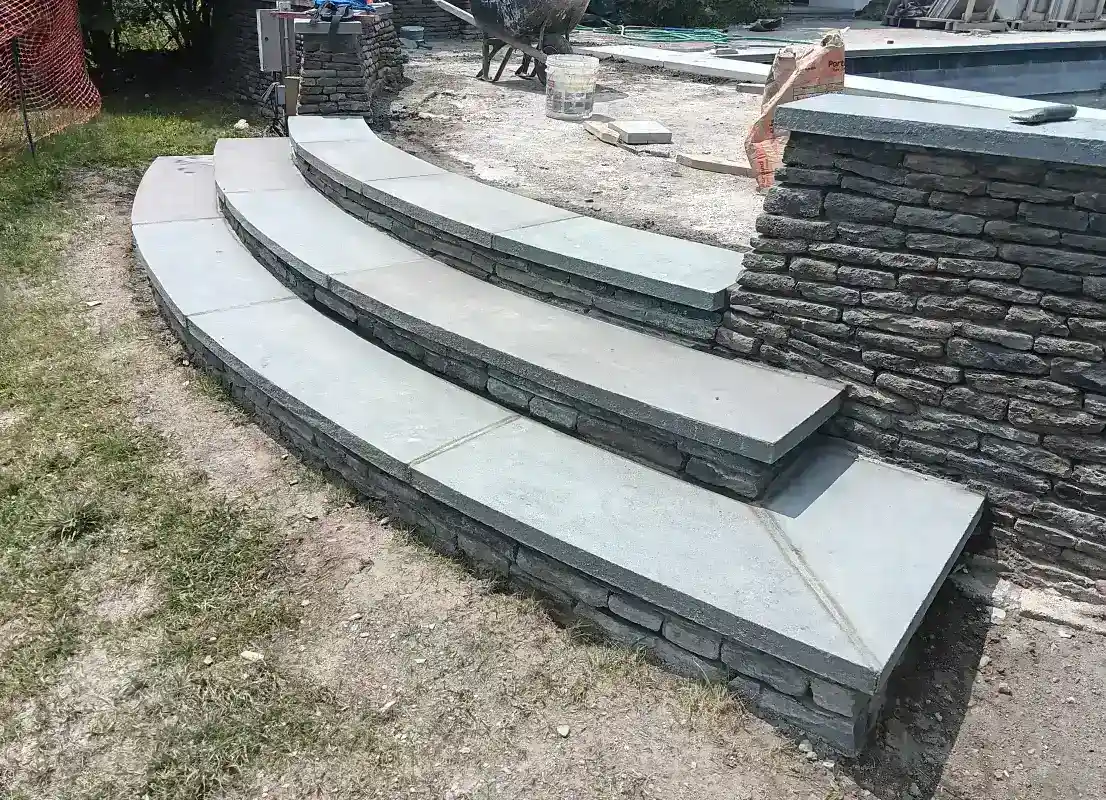 Curved stone steps with retaining wall and poolside setting.