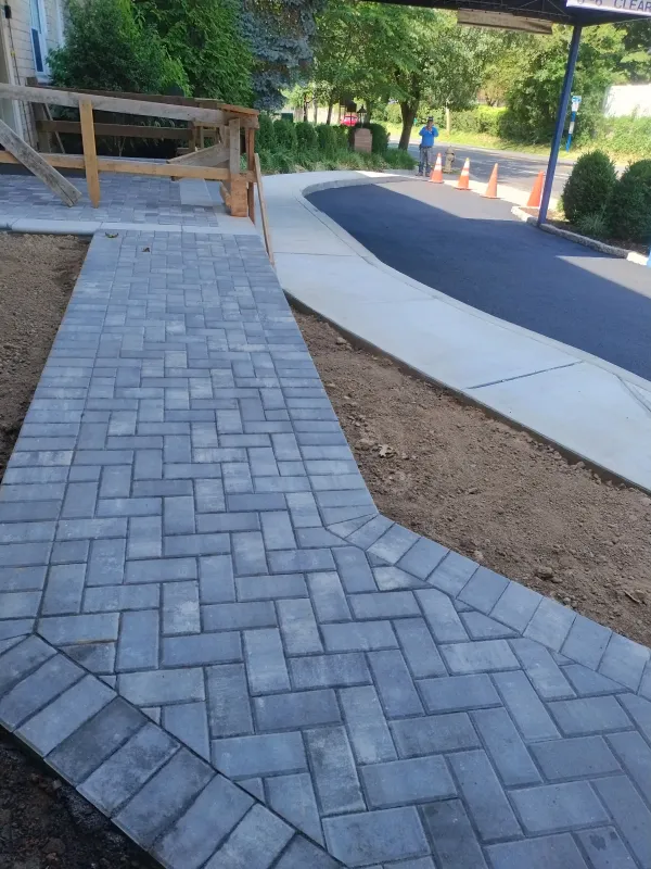 New paved walkway with herringbone pattern and wooden railing.