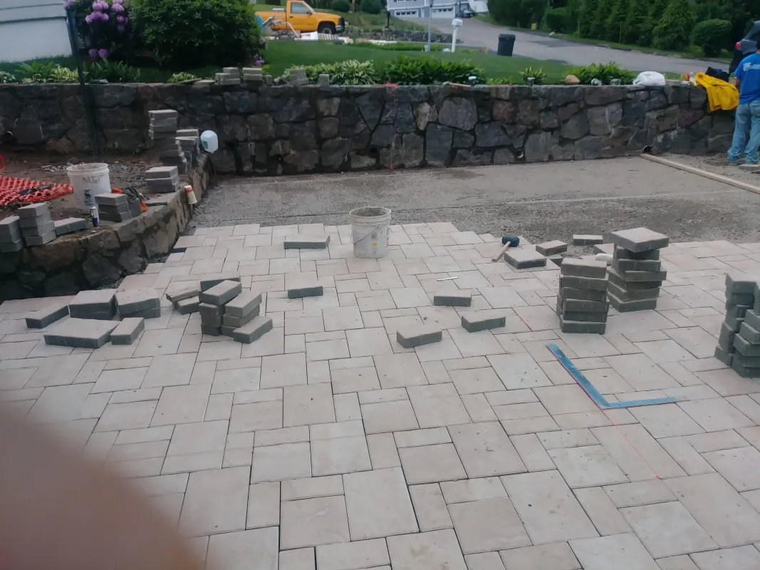 Pavement installation with stone pavers and construction tools.