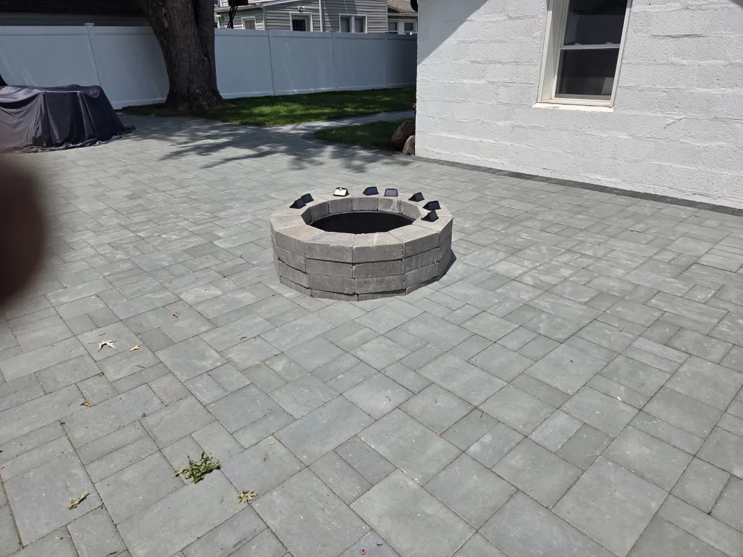 Stone fire pit on paved backyard patio.