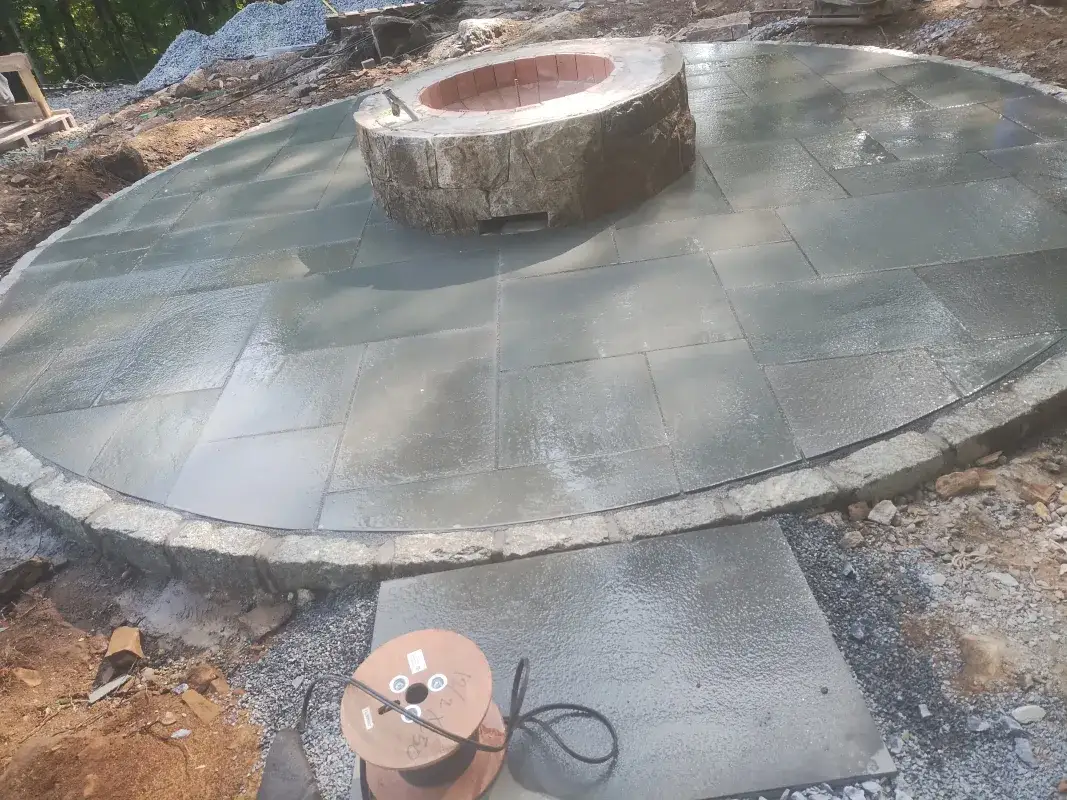 Stone fire pit on newly laid patio surface.