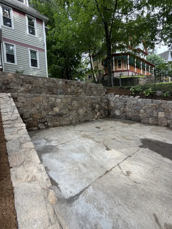 Stone retaining wall with concrete patio area.