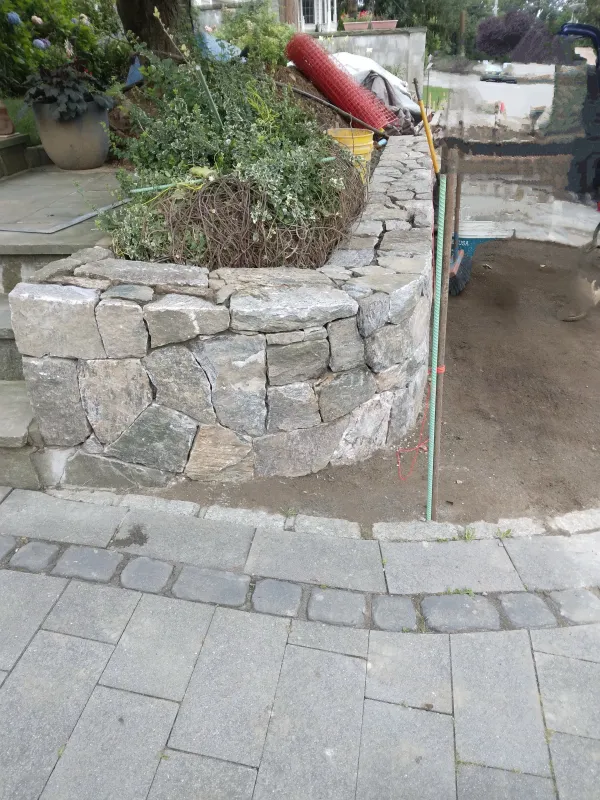 Stone retaining wall under construction with paving stones.