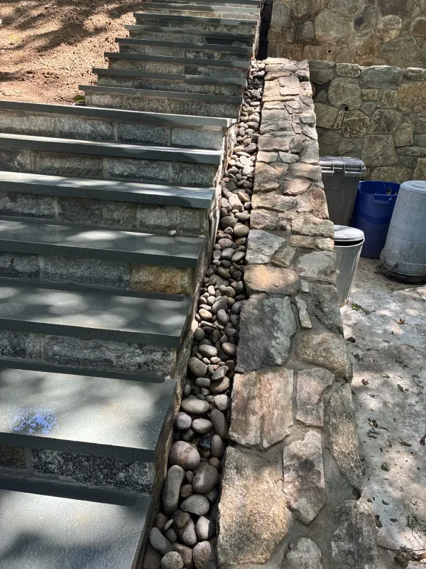 Stone steps with retaining wall and decorative rocks.